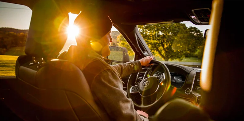 A man driving a 2026 RAM 2500 with the sunrise in the backround.