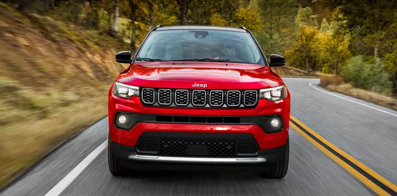 A red 2025 Jeep Compass driving down the road.