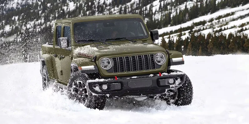 A green 2026 Jeep Gladiator off-roading through snow.