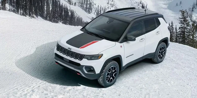 A white 2026 Jeep Compass off-roading through snow.
